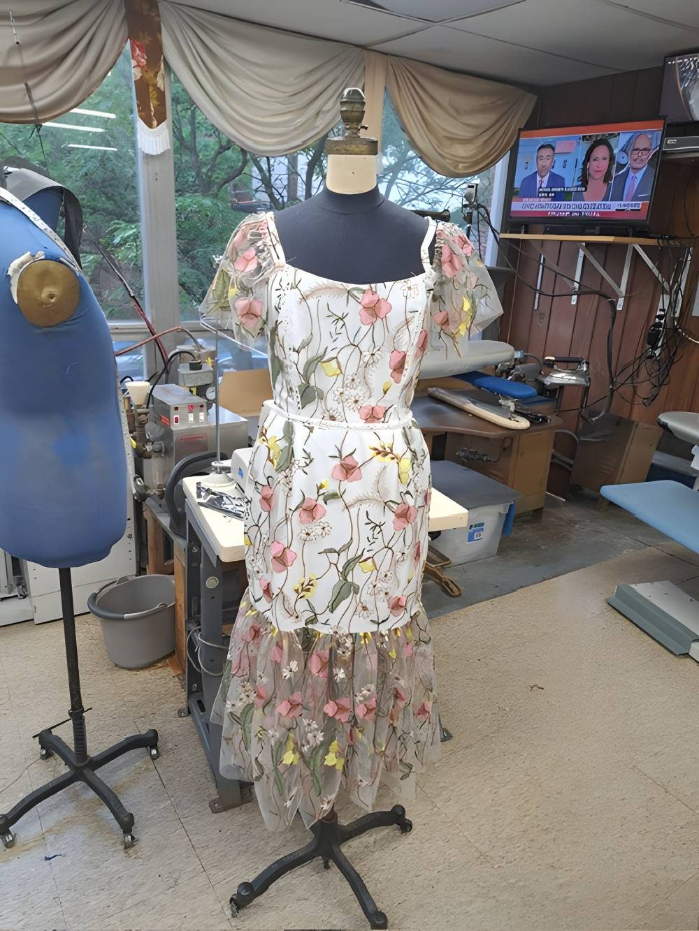 Floral dress on a dress form inside the Tailoring and Alteration Center workroom with pressing equipment